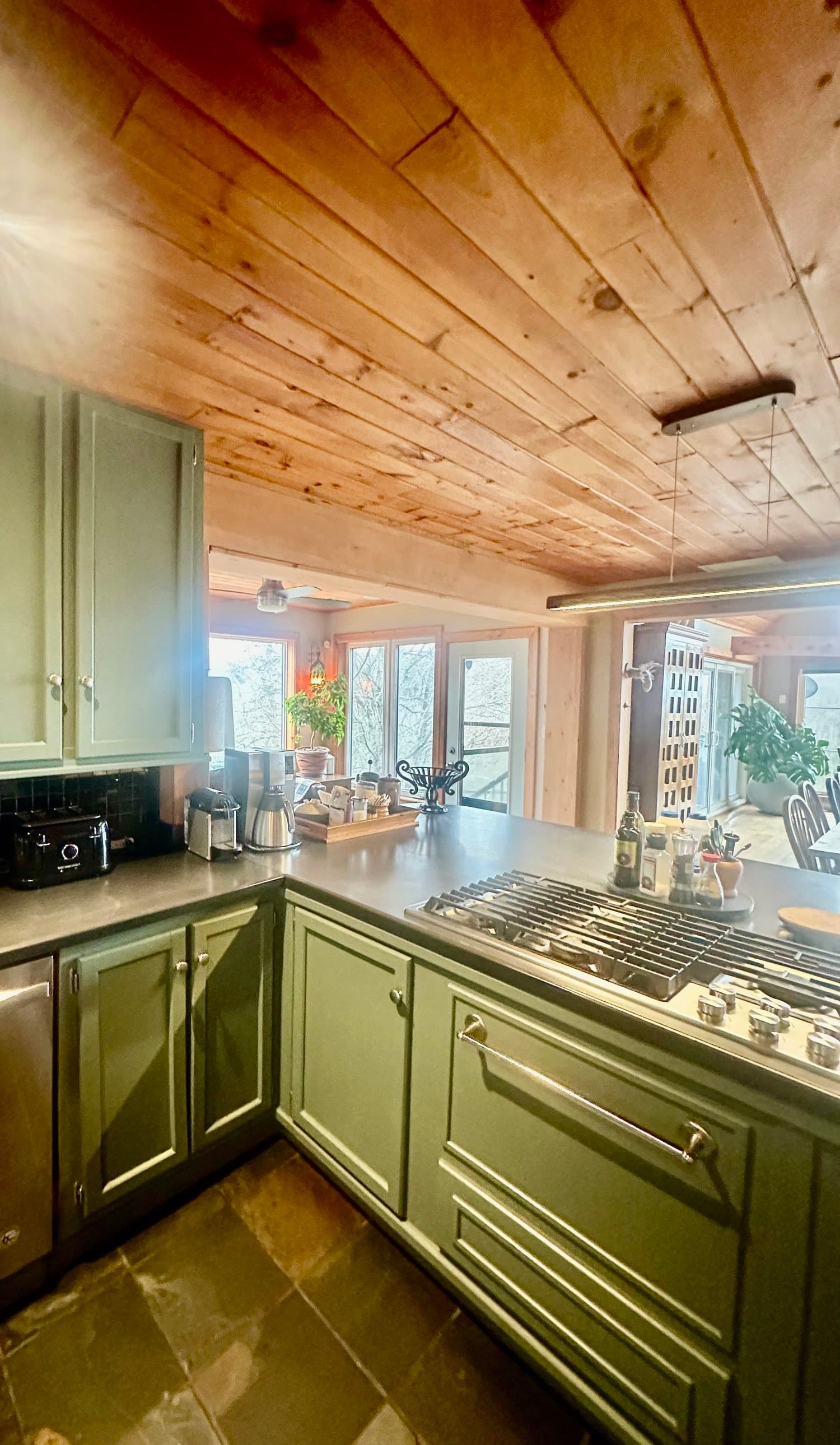 Kitchen counter with gas cooktop under a pine ceiling