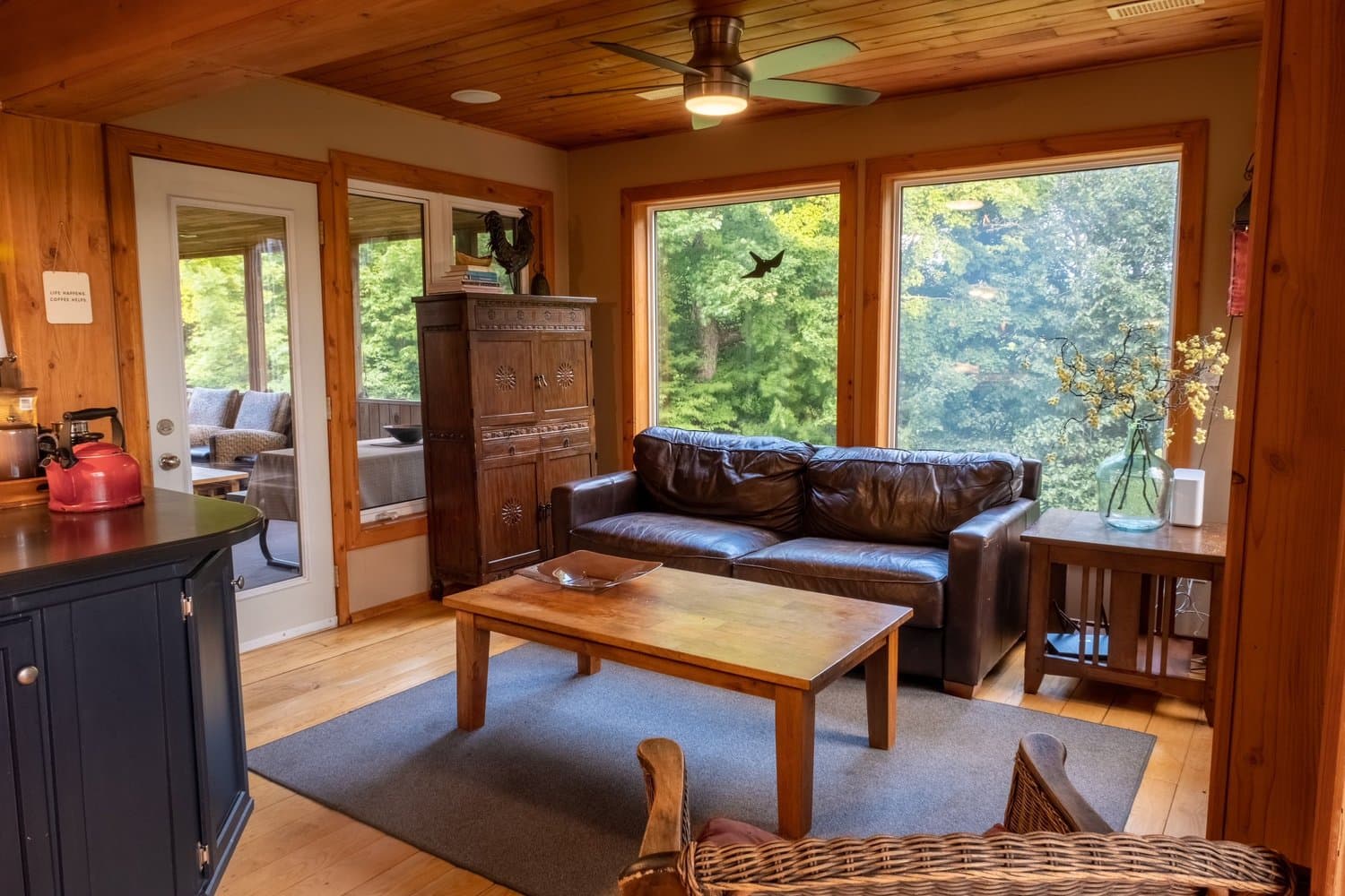 Sitting room with leather sofa and forest-view windows