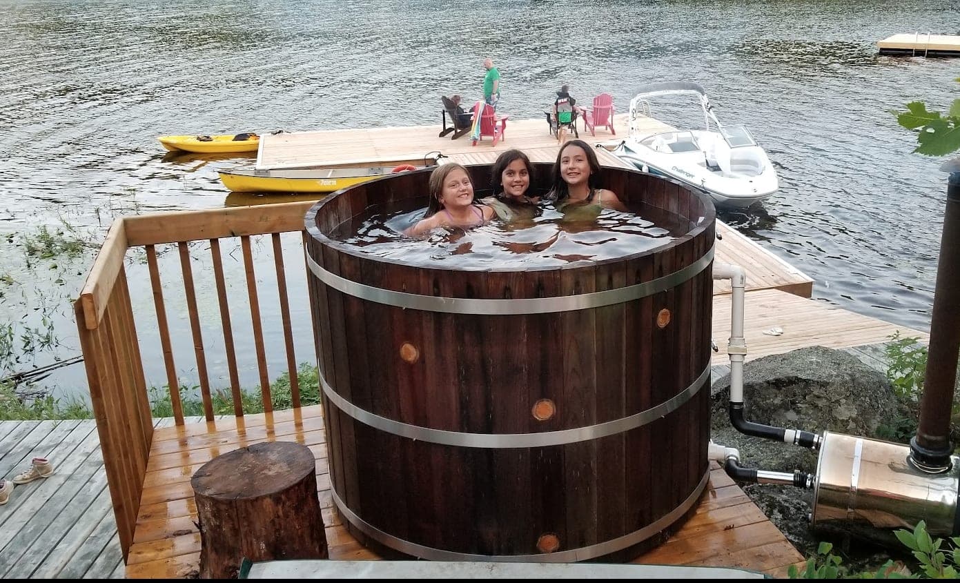 Guests in the cedar hot tub by the water