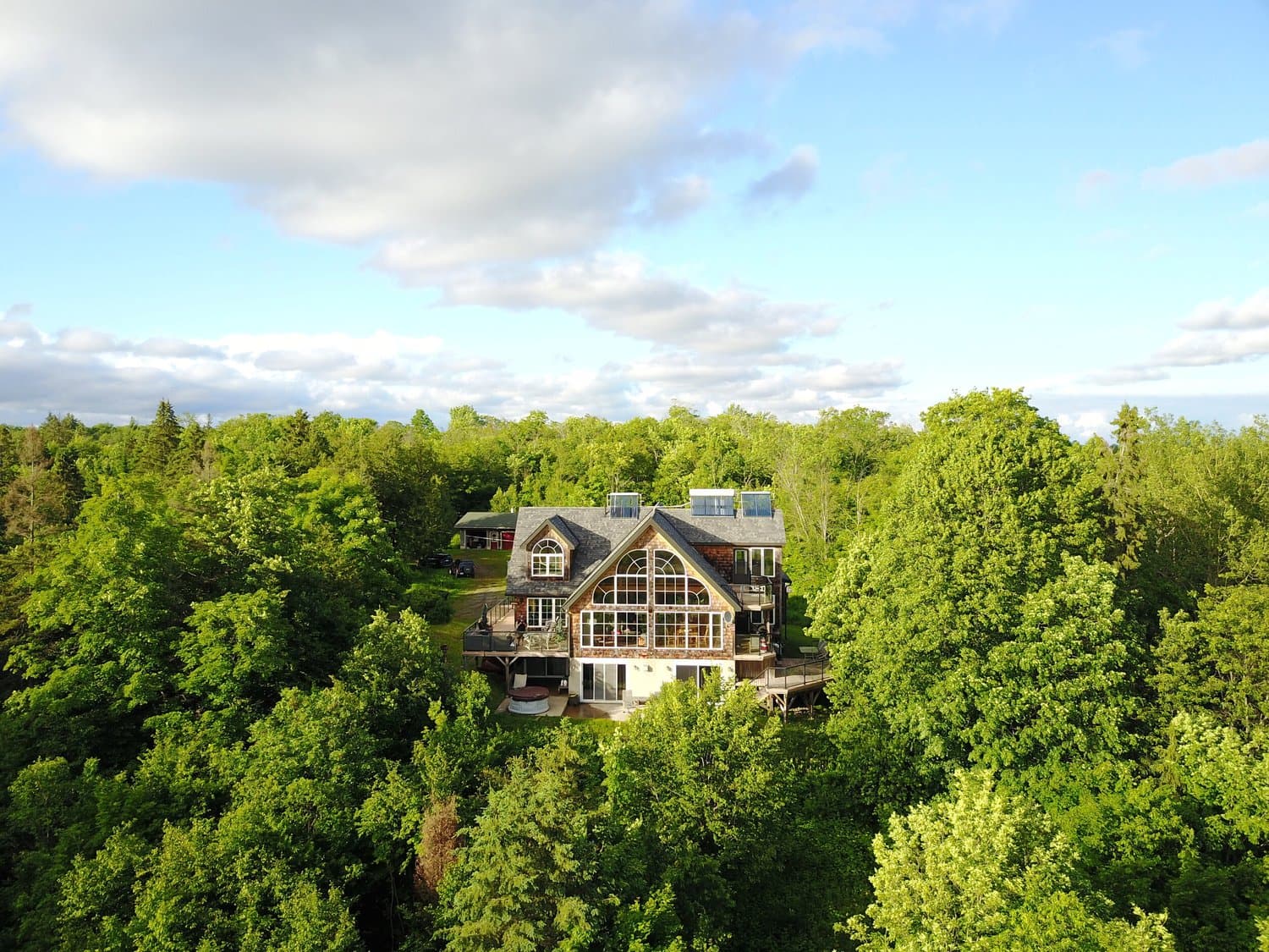 Aerial view of the cottage above the treetops on a summer evening