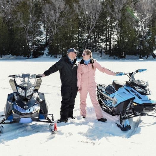 Couple with snowmobiles on the frozen lake