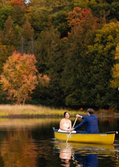 Couple paddling a canoe among fall colours